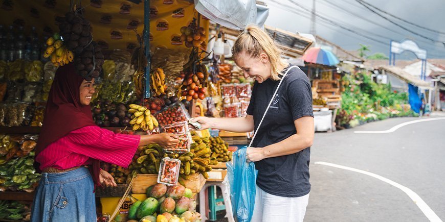 Kvinna i TourCompass-t-shirt betalar kvinna för varor i ett gatustånd