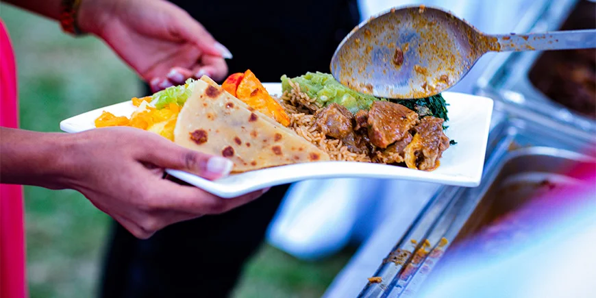 Kvinna som håller en tallrik med mat i Kenya.