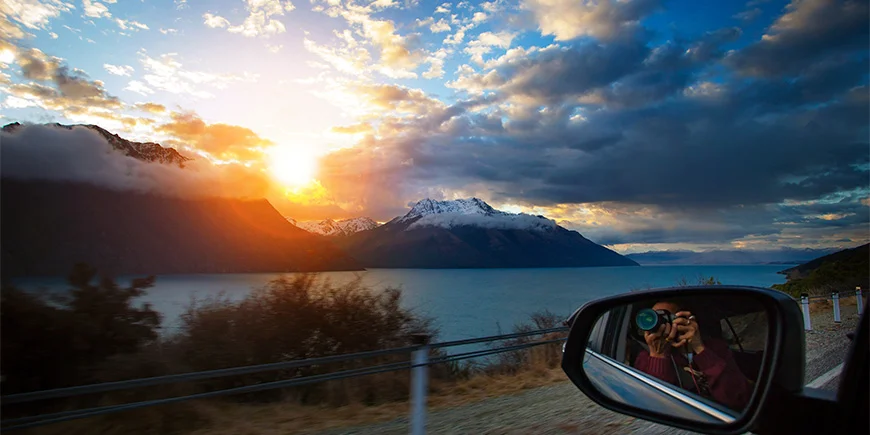 Man tar en bild genom fönstret vid Lake Wakatipu på Sydön i Nya Zeeland