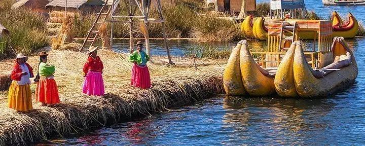 Peruvianska kvinnor i traditionella dräkter hälsar turister välkomna till Uros Island