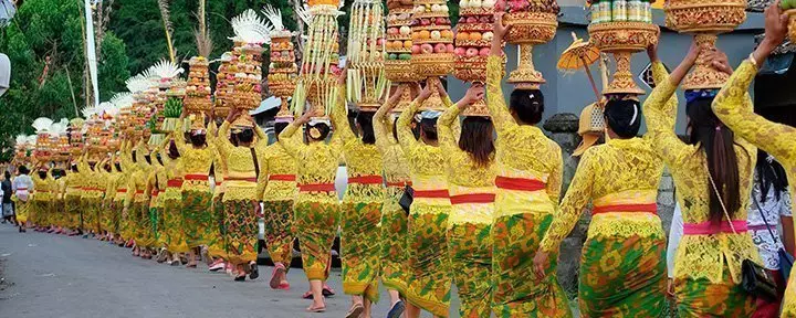 Procession av vackra balinesiska kvinnor i traditionella dräkter på väg till hinduistisk ceremoni i Bali.