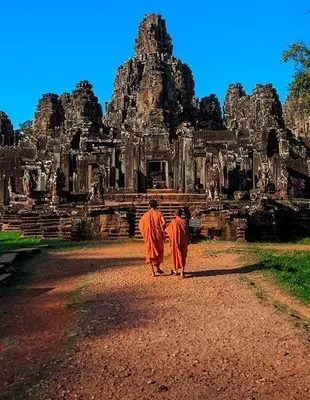 Två munkar framför Bayon-templet vid Angkor i Kambodja