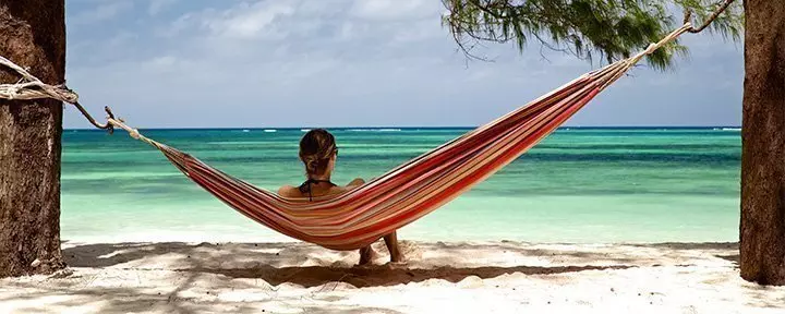 Kvinna ligger i hängmatta på strand i Zanzibar